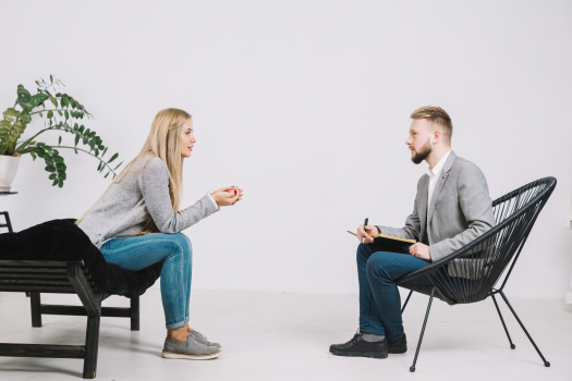 Homme psychologue assis devant une patiente écoutant son problème